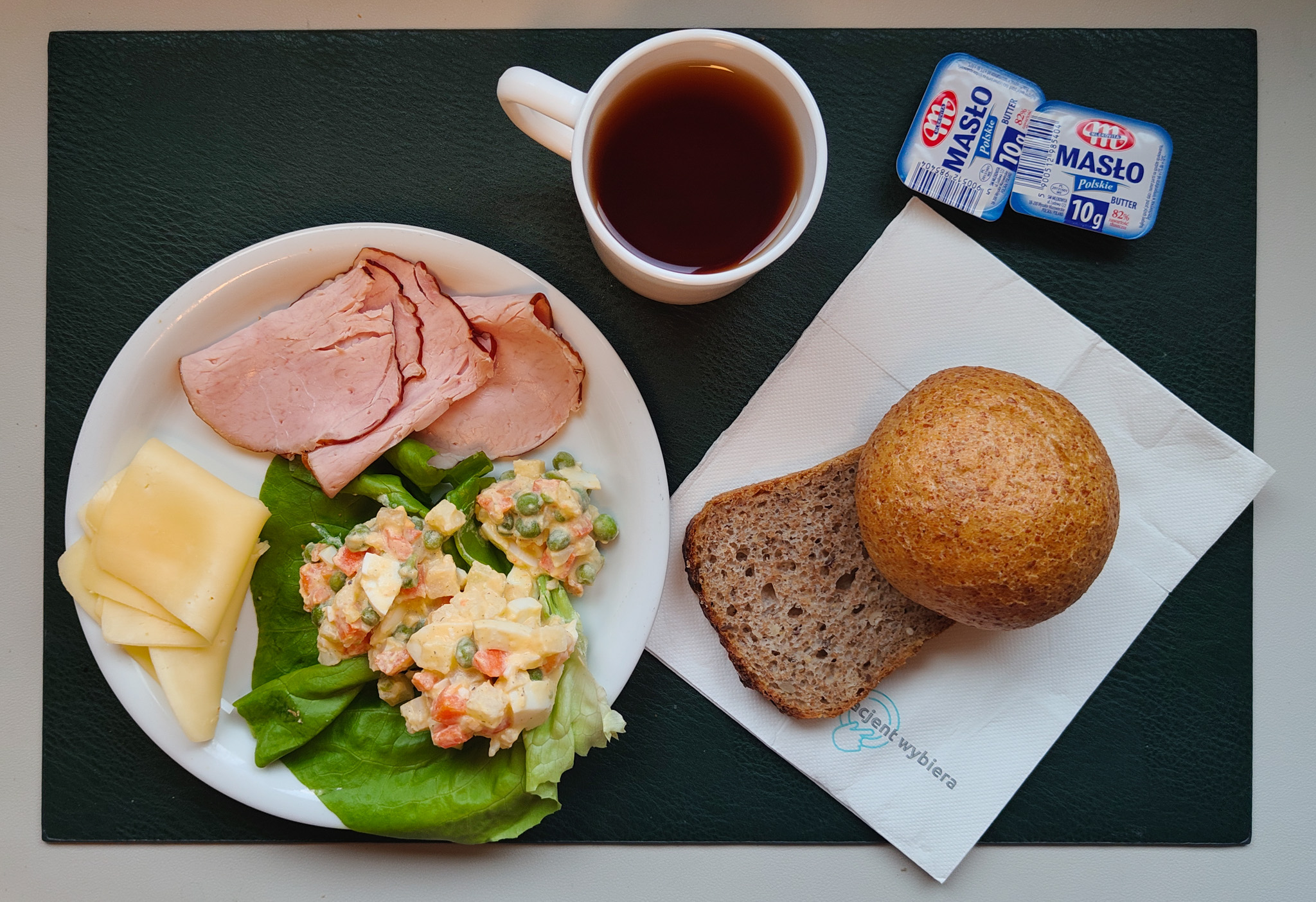 Bułka graham-pszenna 50g 1 szt ( GLU PSZ,) Chleb ze słonecznikiem i lnem-pszenno-żytni 30 g ( GLU PSZ, GLU ŻYT, ) Masło porcjowane 10g (82% tł.) 2 szt ( MLE,) Ser żółty 30 g (MLE,) Schab Kruchy z Liszek- wieprzowy, parzony, wędzony 50 g ( SOJ, może zawierać: GLU PSZ, MLE, SEL, GOR, S02, ) Sałatka jarzynowa z jajkiem dieta + 120 g ( JAJ, MLE, SEL,) Sałata zielona 10 g Herbata czarna ekspresowa z cytryną Cateringowa b/c 250 ml