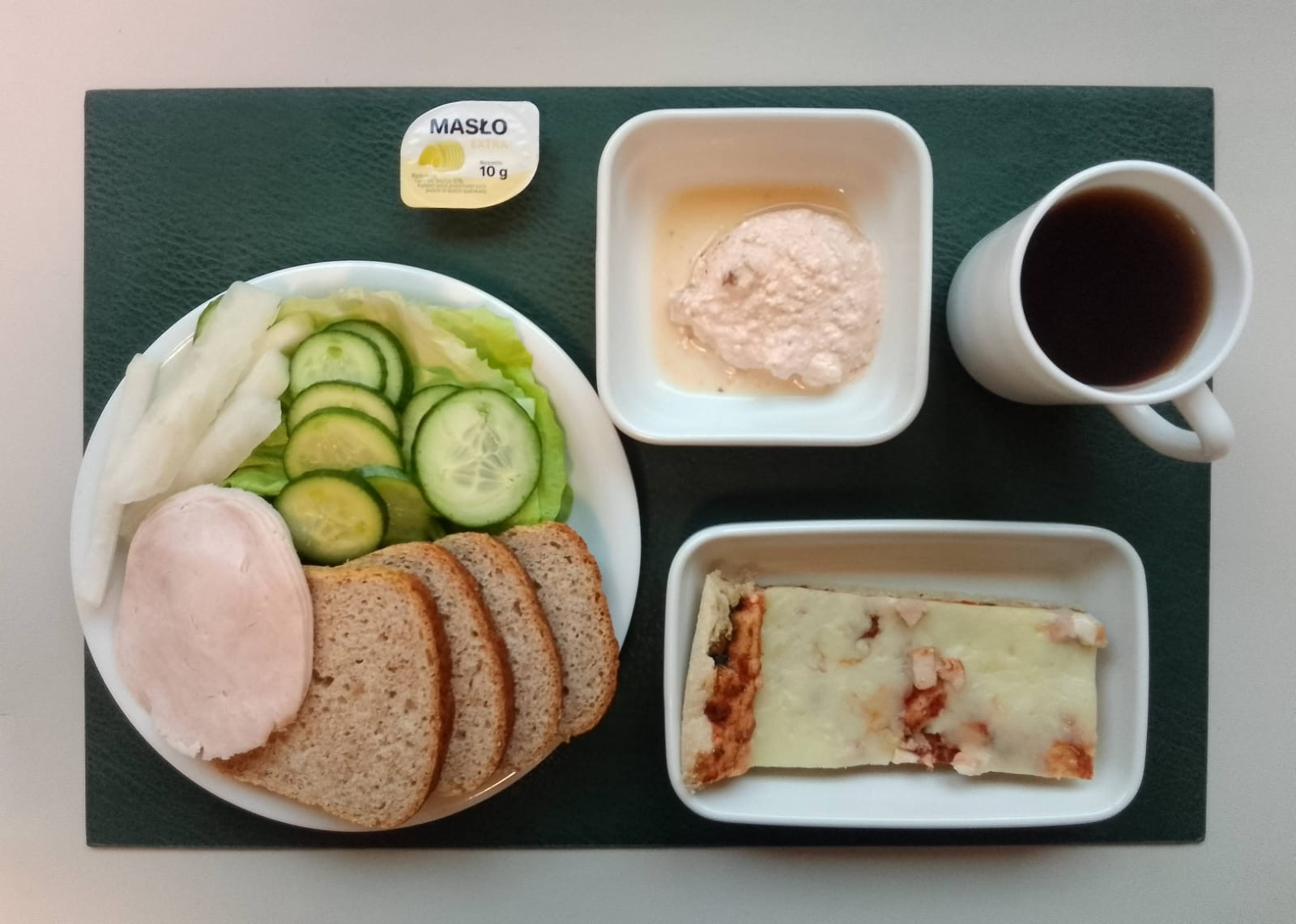 Wytrawny placek z mozzarellą i warzywami a'la pizza + 75 g ( GLU PSZ, SOJ, MLE, ) Chleb Graham 90 g ( GLU PSZ,) Masło porcjowane 10g (82% tł.) 1 szt ( MLE,) Twarożek pomidorowy + 50 g ( MLE,) Szynkowa dębowa drobiowa kiełbasa grubo rozdrobniona 50 g Plastry ogórka świeżego + 50 g Słupki rzodkwi białej + 50 g Sałata zielona 20 g Herbata czarna ekspresowa z cytryną Cat