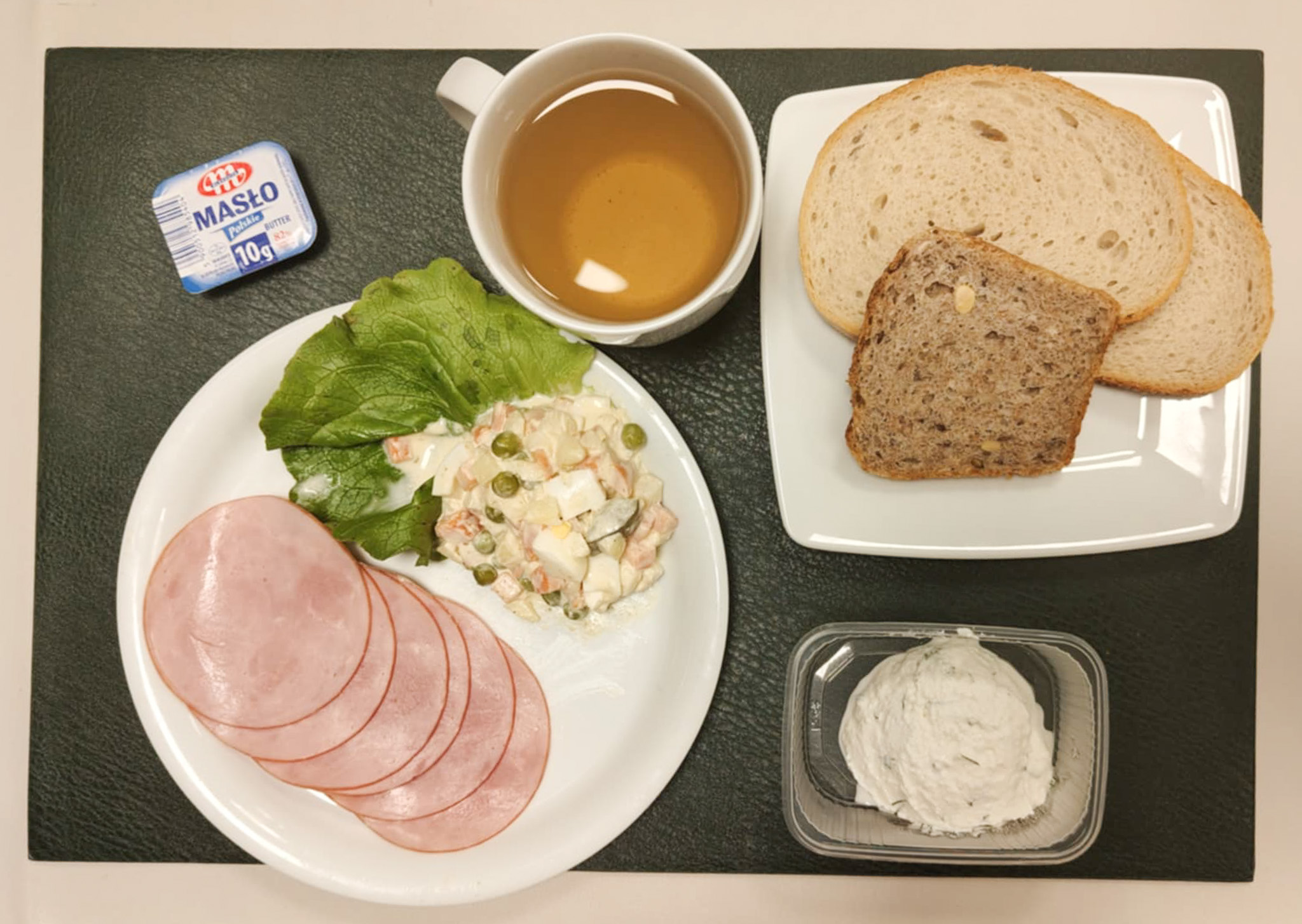 Chleb mieszany pszenno-żytni 50 g ( GLU PSZ, GLU ŻYT, ) Bułka pszenna długa krojona 30 g ( GLU PSZ,) Masło porcjowane 10g (82% tł.) 2 szt ( MLE,) Pasta z twarogu z koperkiem + 50 g ( MLE,) Szynkowa dębowa kieł.wp.gr.rozd.wędz.parzo.z dodat.wody w osł.niejad 50 g Sałatka jarzynowa z jajkiem dieta + 120 g ( JAJ, MLE, SEL,) Sałata zielona 10 g Herbata czarna ekspresowa z cytryną Cateringowa b/c 250 ml Cukier 5 g