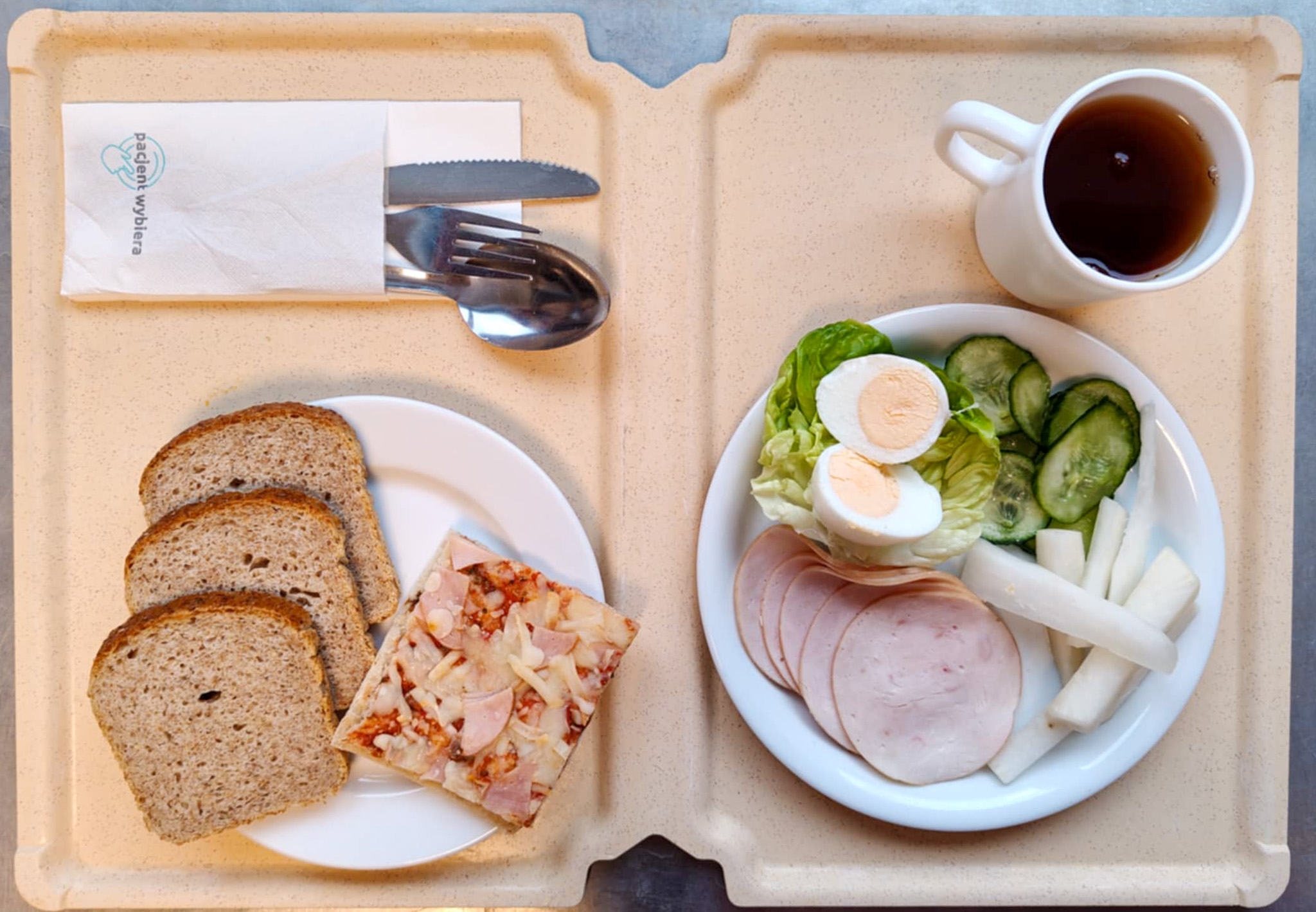 Wytrawny placek z mozzarellą i warzywami a'la pizza + 75 g ( GLU PSZ, SOJ, MLE, ) Chleb Graham 90 g ( GLU PSZ,) Masło porcjowane 10g (82% tł.) 1 szt ( MLE,) Jajko gotowane kl M + 1 szt ( JAJ,) Szynkowa dębowa drobiowa kiełbasa grubo rozdrobniona 50 g Plastry ogórka świeżego + 50 g Słupki rzodkwi białej + 50 g Sałata zielona 20 g Herbata czarna ekspresowa z cytryną Cateringowa b/c 250 ml Cukier 5 g