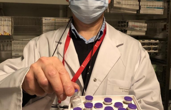 Zbliżenie na pracownika arietki trzymającego pudełko ze szczepionkami 